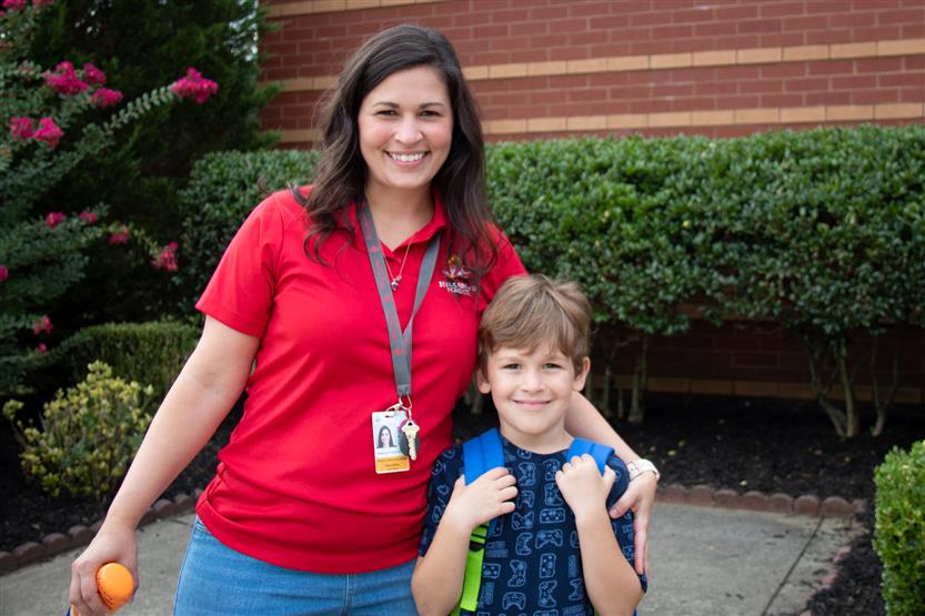 A staff members smiles next to a student
